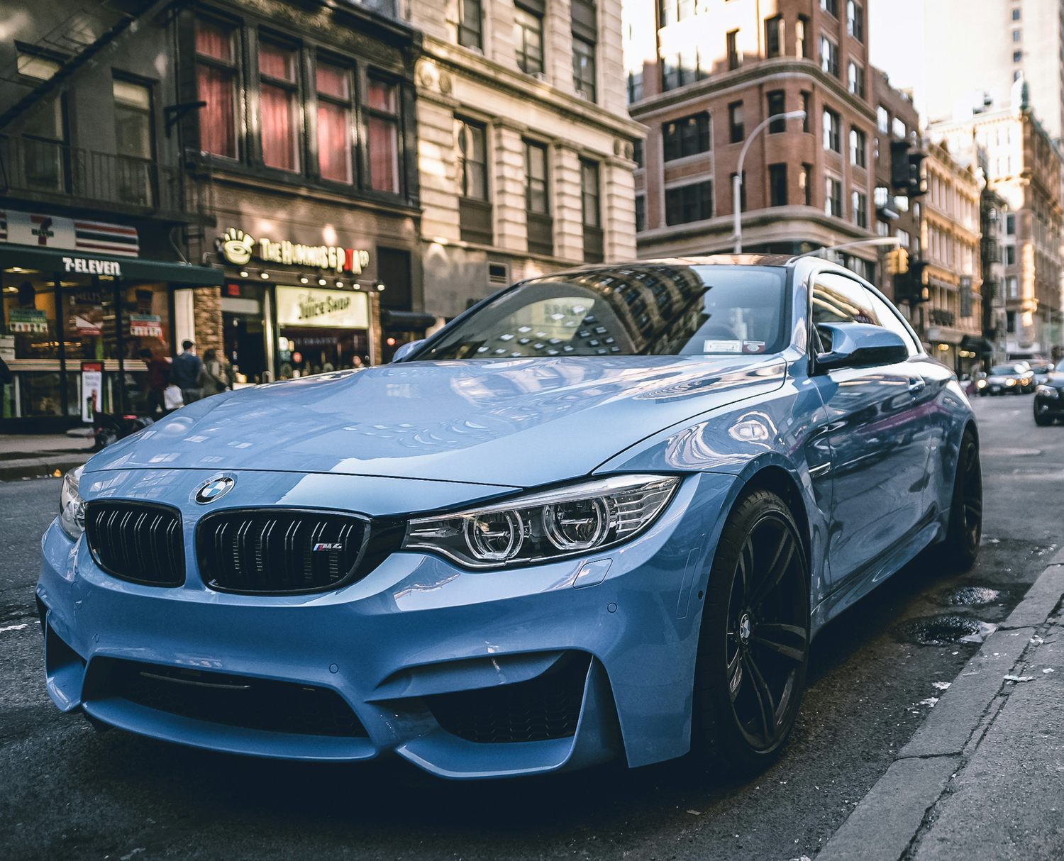Blue BMW with wheel spacers fitted on busy street